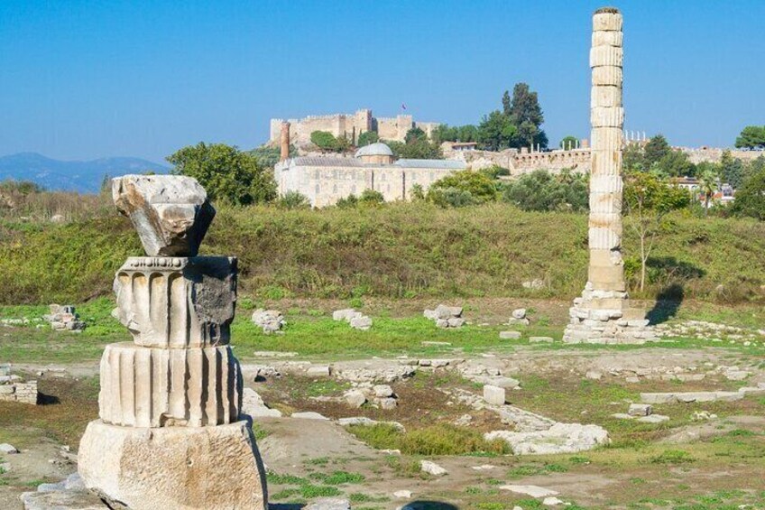 Ancient ruins with stone columns and a castle in the background. 5