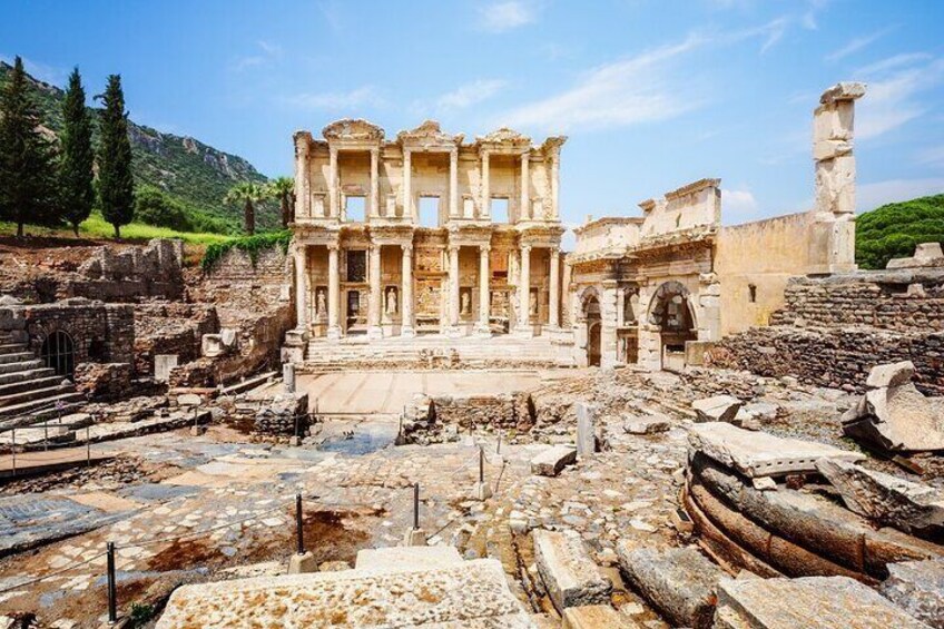 Ancient ruins with columns and arches, surrounded by stone steps and a mountainous backdrop. 2