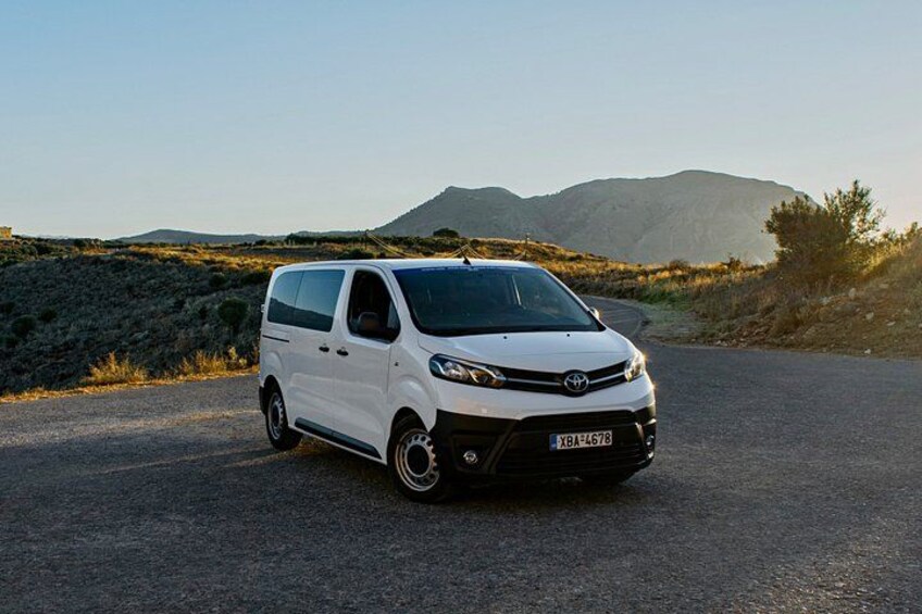 A white van parked on a road with a mountainous landscape in the background. 3