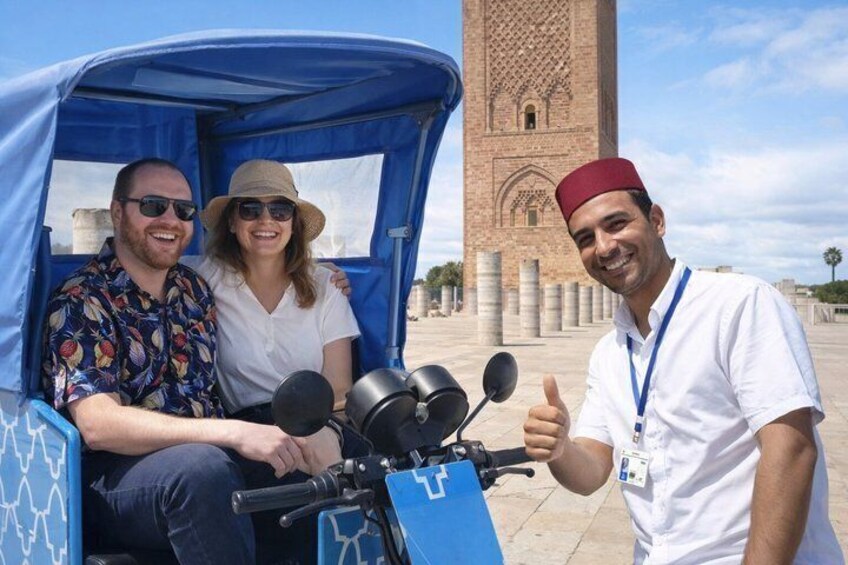 A tuk-tuk with passengers and a person giving a thumbs-up. 1