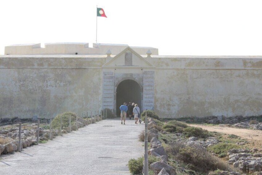 A building with a flag, a paved entrance, and a stone archway. 4