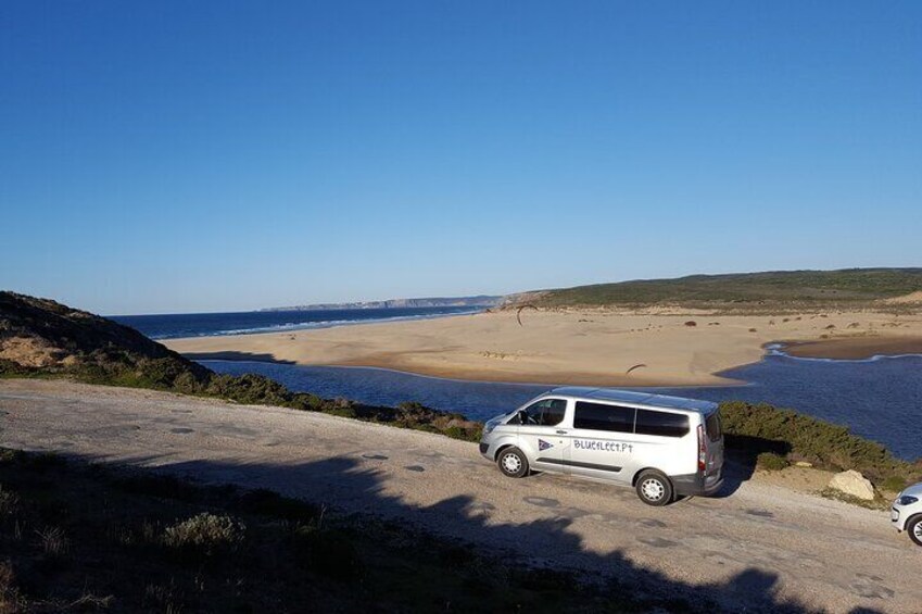 A white van parked on a dirt road with a coastal landscape in the background. 1