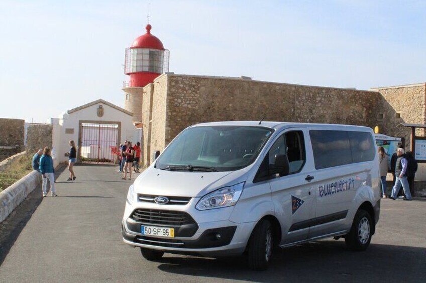 A white van with "Blueflood" on the side parked in front of a building with a red and white lighthouse. 3