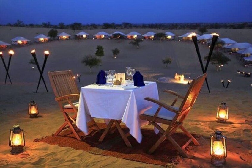 A desert dining setup with a table, chairs, and lanterns. 1