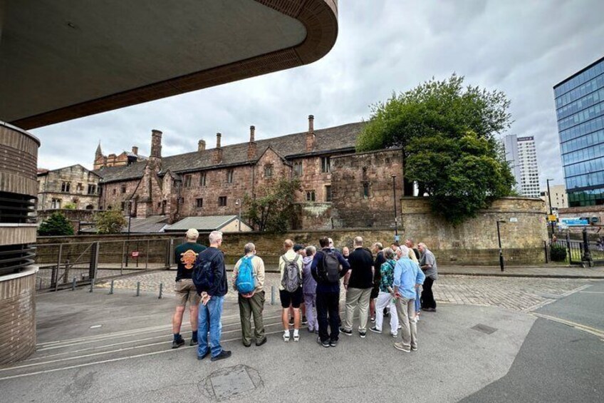 Eine Gruppe von Menschen steht in einem Innenhof vor historischen Gebäuden. 3
