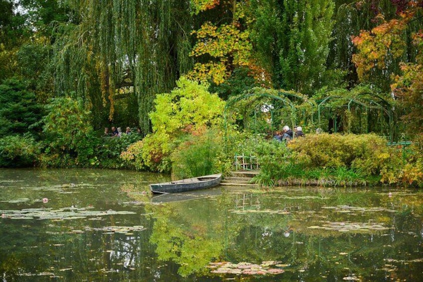 Un río tranquilo con una barca pequeña, vegetación exuberante y un puente. 3