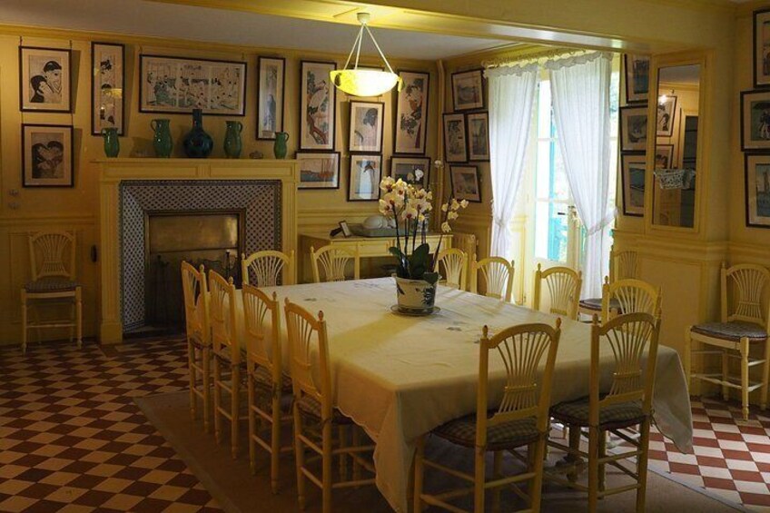 A dining room with a checkered floor, a large table, chairs, a fireplace, and framed pictures on the walls. 5