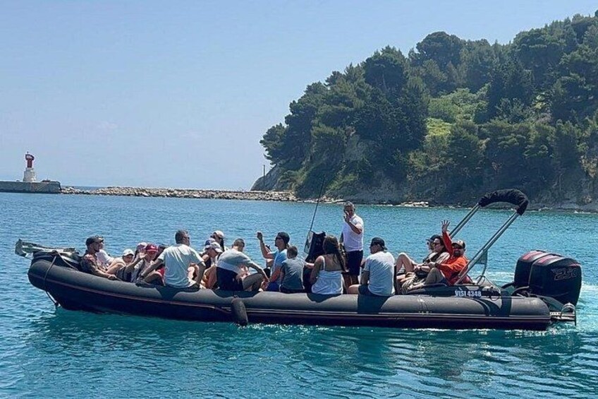 A group of people on a motorboat near a lighthouse and a forested island. 1