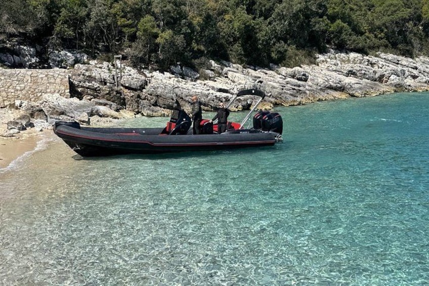 A motorboat on clear turquoise water near a rocky shoreline with trees in the background. 5