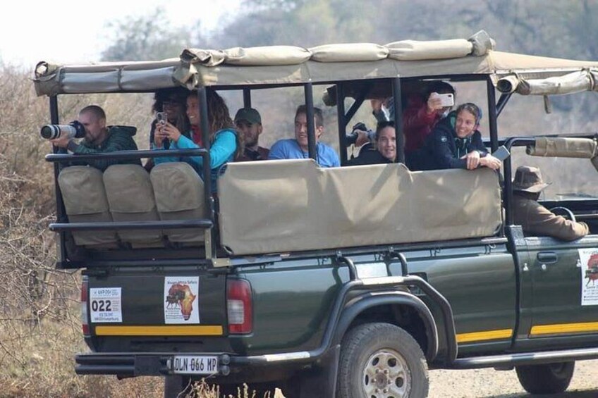 A safari vehicle with passengers, a license plate, and a registration sticker. 4