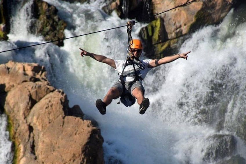 A person zip-lining over a waterfall. 2