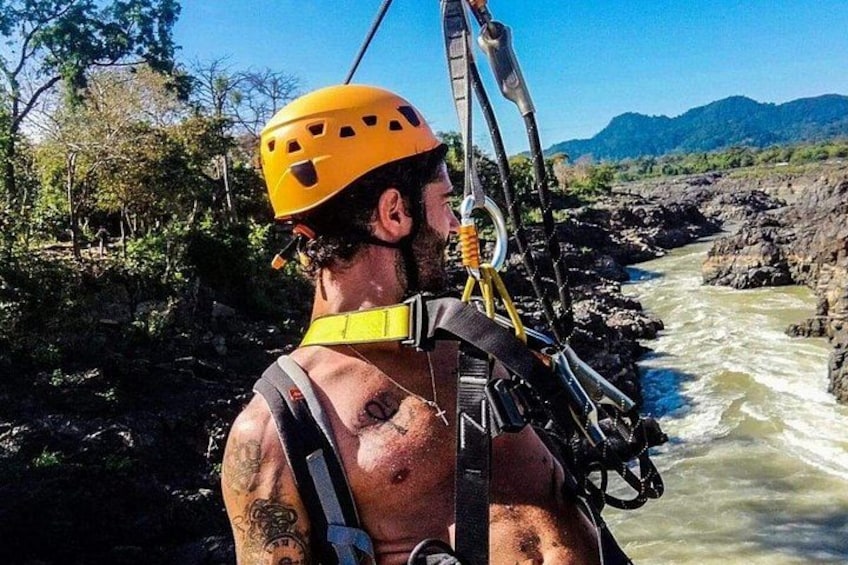 A person rappelling down a river with a helmet and harness. 1