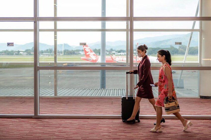 Two people walking inside a building with large windows overlooking a runway. 1