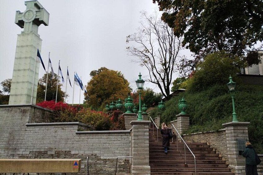 A stone monument with flags, a staircase, and green street lamps. 3