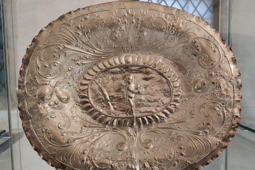 A detailed metal plate with intricate designs and a central scene. 2
