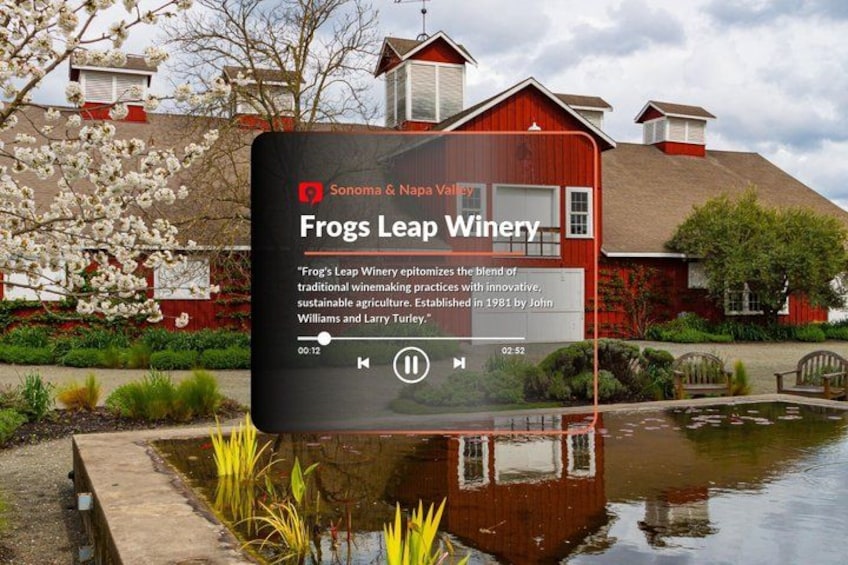 A winery sign with a pond and red buildings in the background. 2
