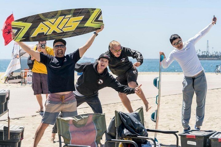 A group of people on a beach holding a large surfboard with the word 'AXISL' on it. 5