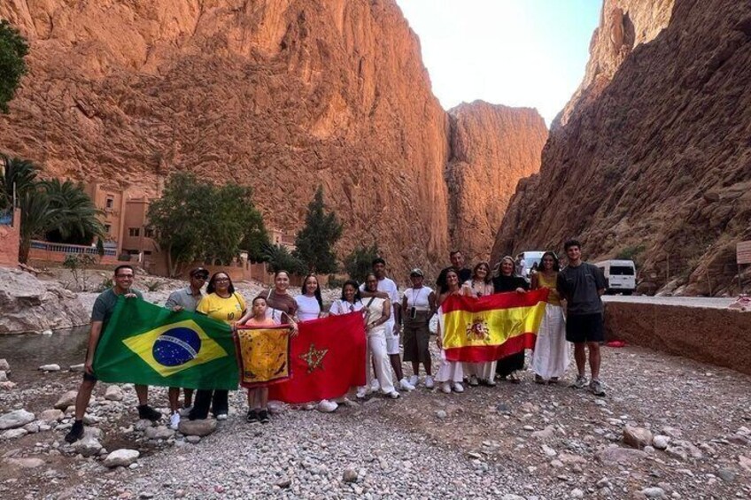 A group of people standing in a rocky canyon with a river, holding flags. 4
