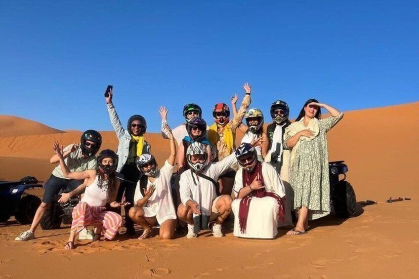 A group of people in a desert with sand dunes in the background. 3