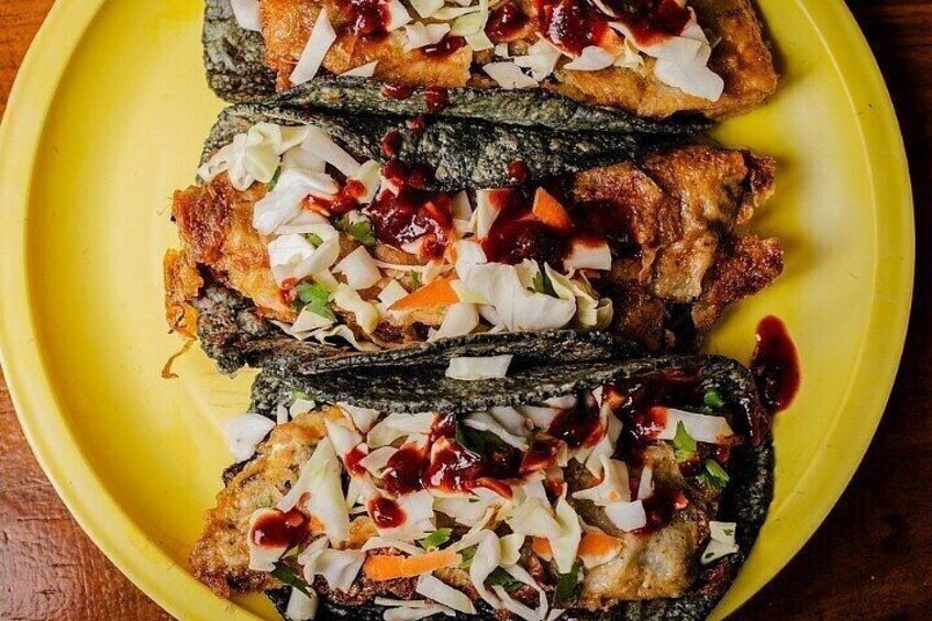 A yellow plate with three pieces of fried fish topped with coleslaw and a red sauce. 3