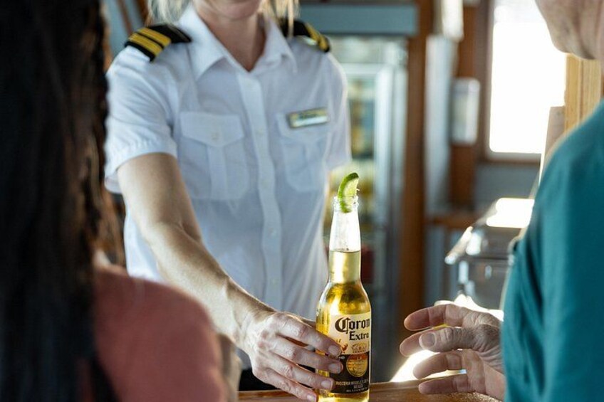 A person handing a Corona beer bottle to another person. 2