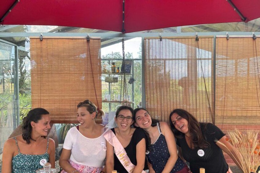 Een groep mensen zit onder een rode luifel bij een evenementenlocatie buiten. 1