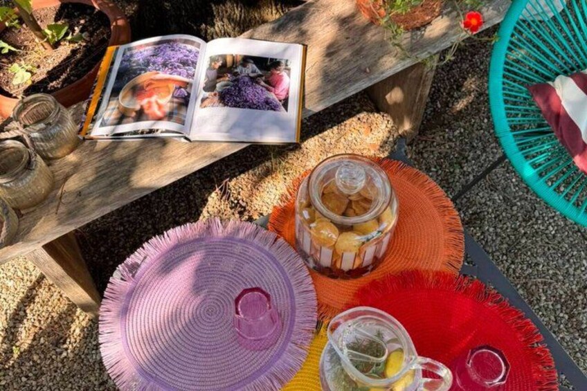 Een houten tafel met een boek, potten en kleurrijke geweven placemats. 2