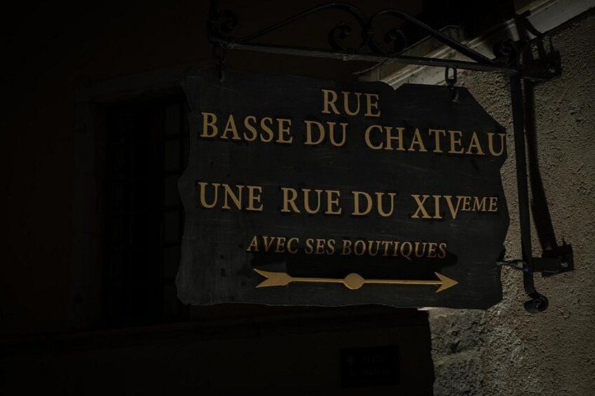 En skylt med texten ”RUE BASSE DU CHATEAU” och en pil som pekar åt höger. 3