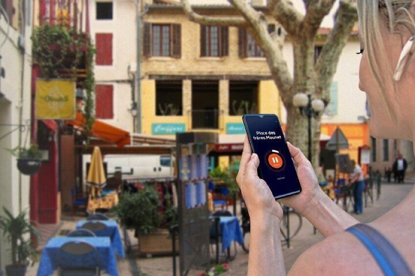 A person holding a smartphone with a map application open, in a street with buildings and outdoor seating. 5