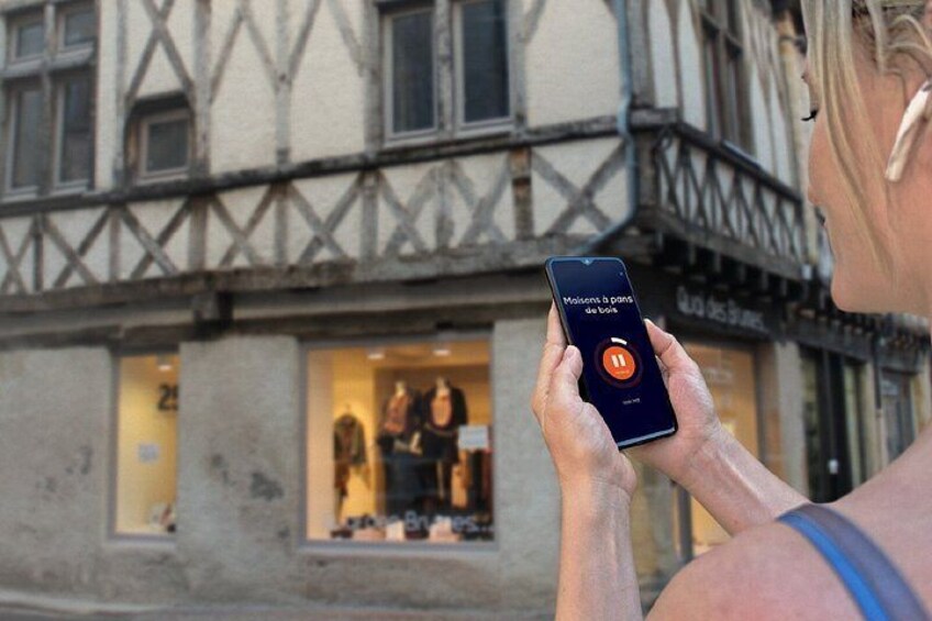 Una persona sosteniendo un teléfono inteligente con una aplicación de mapas abierta, de pie frente a un edificio con un escaparate que exhibe ropa. 5