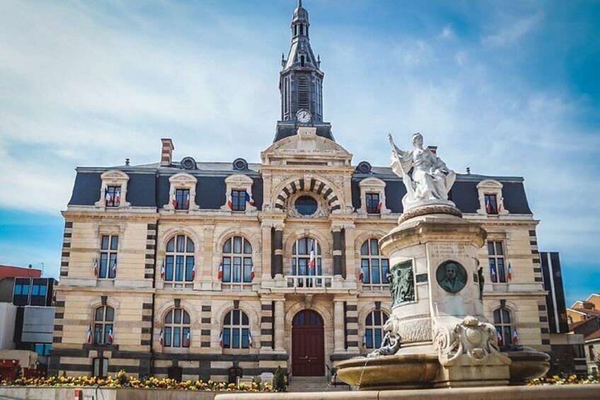 Un edificio histórico con una torre de reloj, estatuas y una fuente. 4