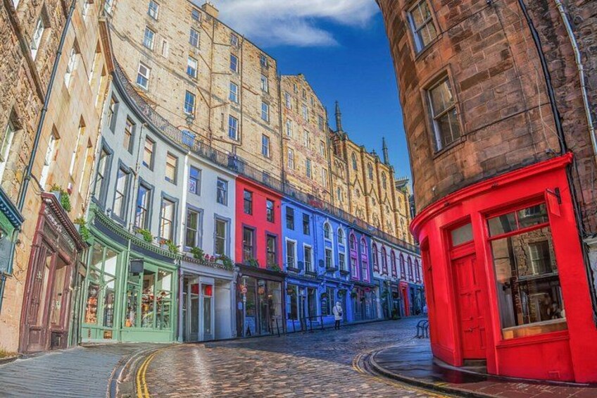 A cobblestone street lined with colorful buildings, a red telephone booth, and a historic building in the background. 4