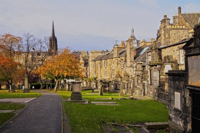 A historic town with stone buildings, a church spire, and a cemetery. 2