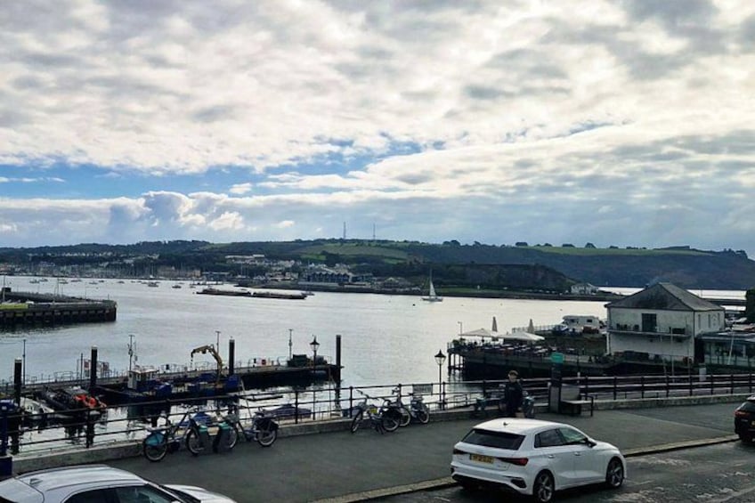 A harbor with boats, a white car, bicycles, and a building. 1