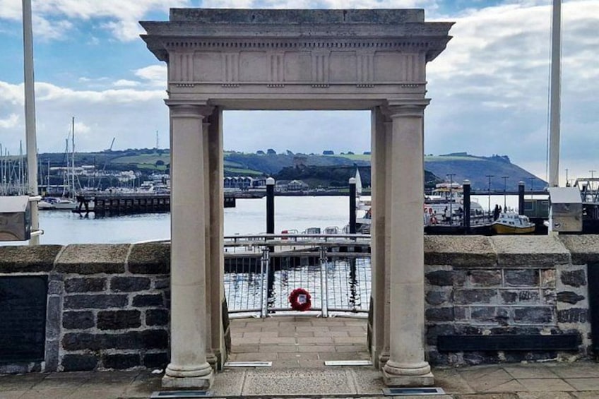 A stone archway with a view of a harbor, boats, and a distant hill. 2