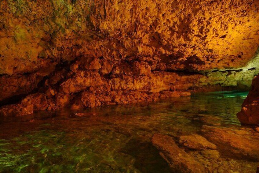 A cave interior with clear water and rocky formations. 1