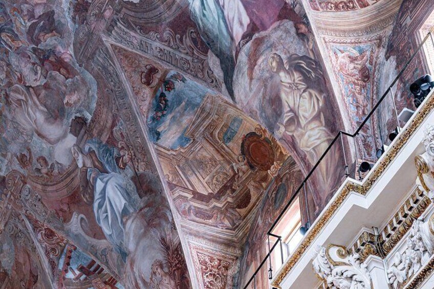 Eine kunstvolle Decke mit aufwendigen Fresken und architektonischen Details. 4