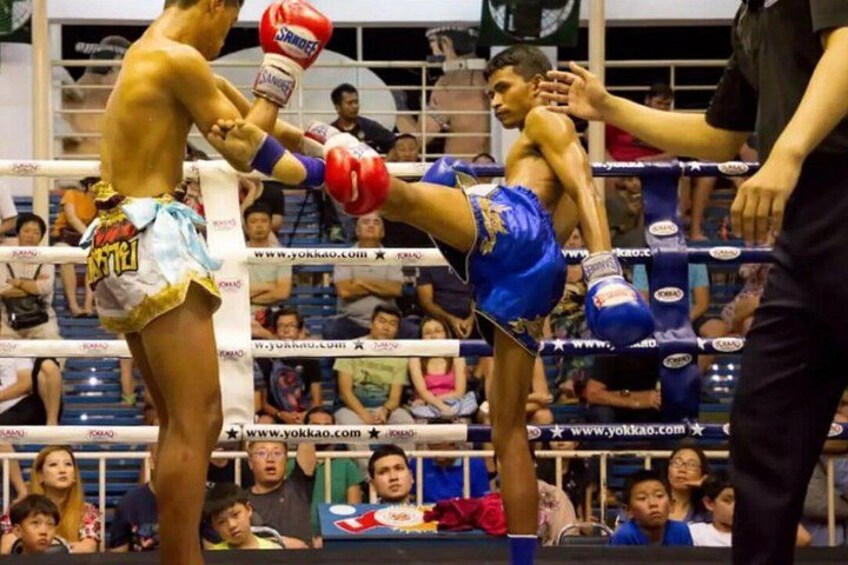 Ein laufender Boxkampf mit zwei Kämpfern in der Ring, einer trägt blaue Shorts und rote Handschuhe, der andere weiße Shorts mit gelben Akzenten. 4