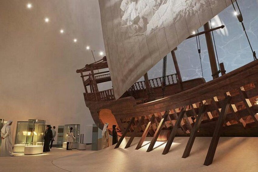 A large ship model displayed indoors with visitors observing it. 4