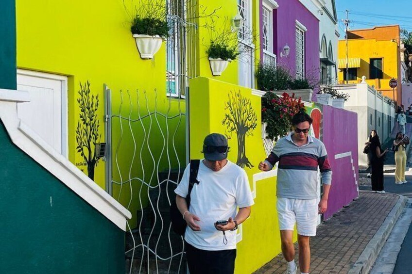 A street with colorful buildings, a metal fence, and a person walking. 5