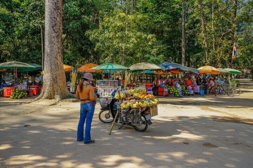 Une scène de marché où des vendeurs, abrités sous des parasols, proposent à la vente des fruits et des légumes. 4