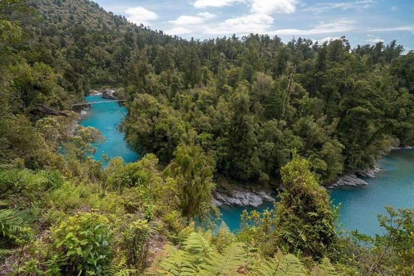 A turquoise river winding through a dense forested valley with rocky outcrops. 2