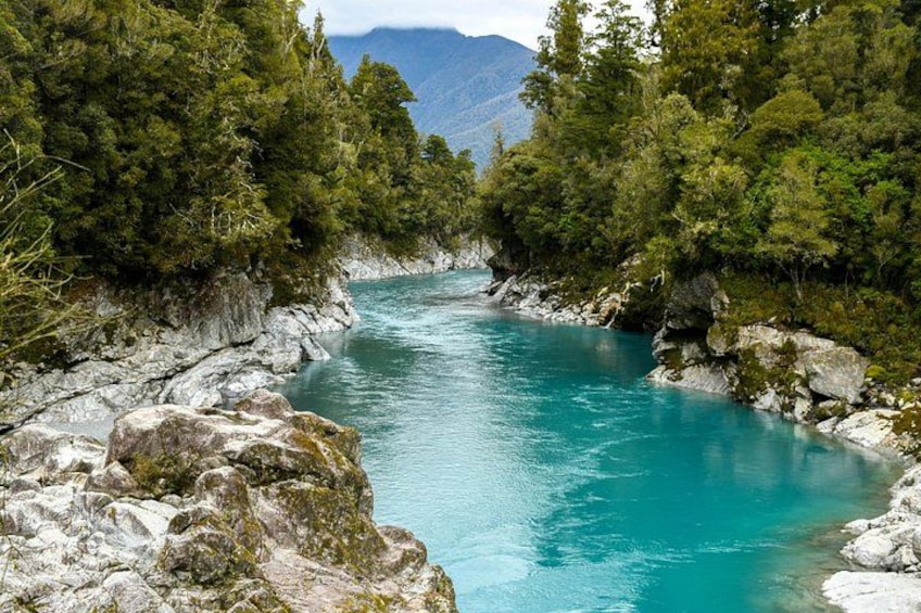 A river surrounded by rocky terrain and dense green forest. 1