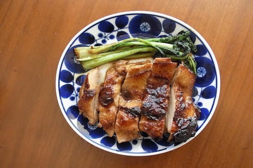 Un plato de pollo asado en rodajas con verduras sobre un plato blanco y azul estampado. 4