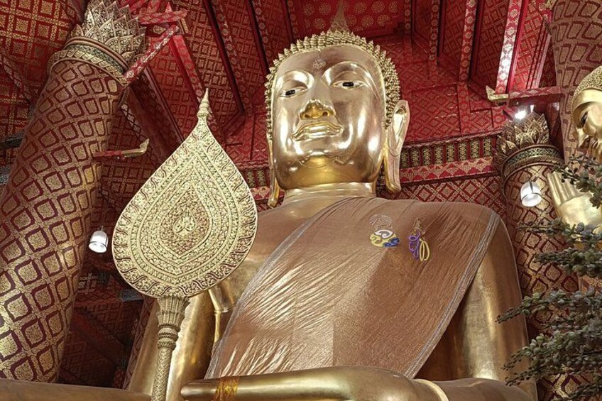 A large golden statue of a seated figure with a headdress, surrounded by intricate patterns and a red ceiling. 2