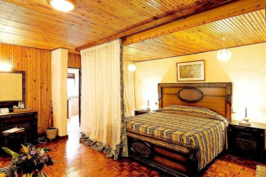 A wooden-paneled bedroom with a large bed, a dresser, and a mirror. 3
