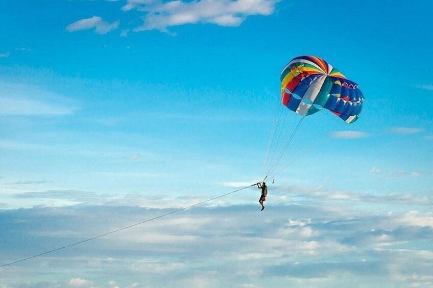 A person skydiving with a colorful parachute above a cloudy sky. 3