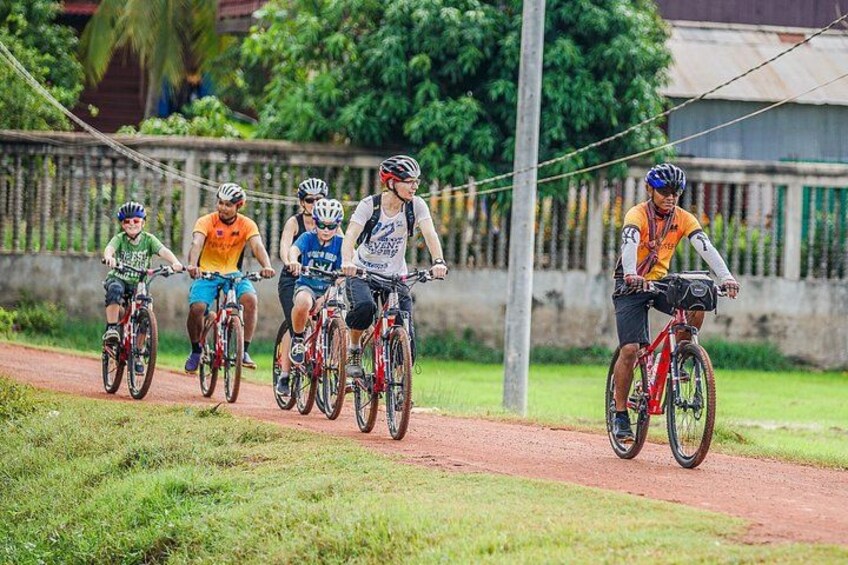 Un grupo de ciclistas en un camino pavimentado, con vegetación a los lados. 1