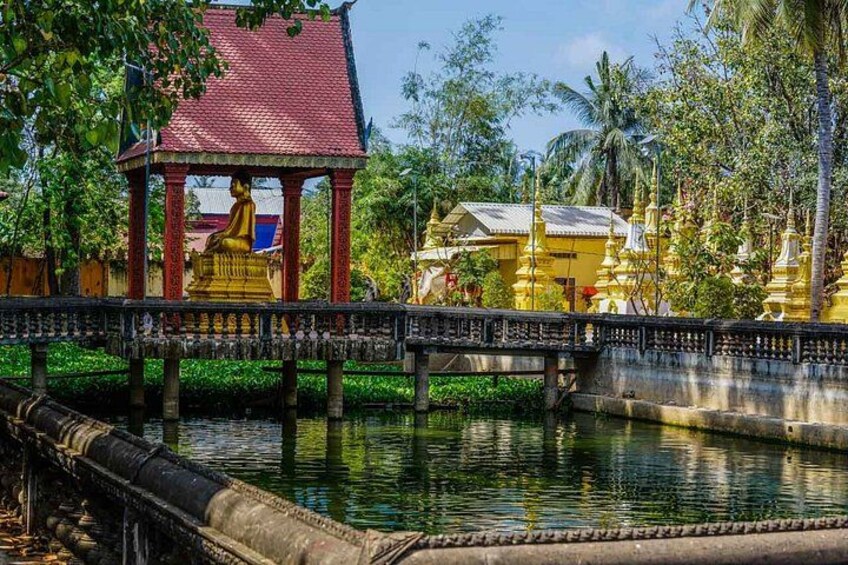 Un templo con una estatua dorada, un puente y un cuerpo de agua. 4
