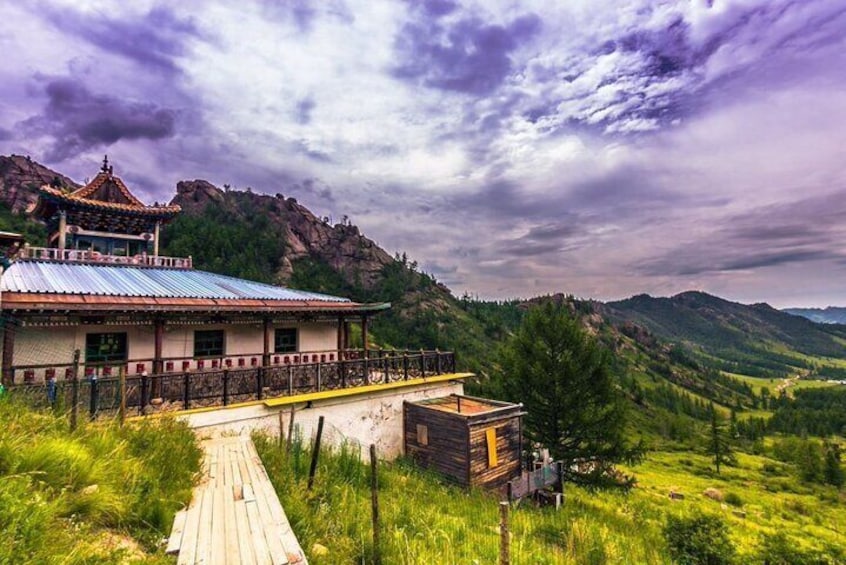 A traditional building with a red roof, a wooden walkway, and a mountainous backdrop. 1